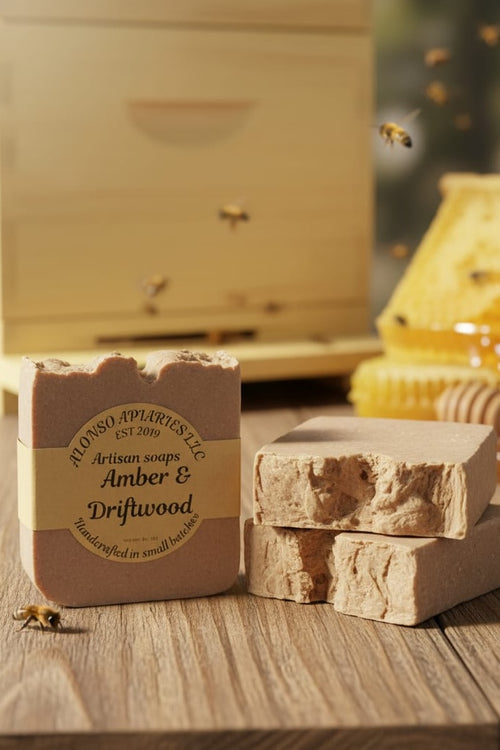 Bar of soap with 'Alonso Apothecaries' branding on a wooden surface with a beehive in the background.