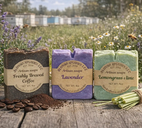 Three artisan soap bars with labels in a field with lavender and flowers.